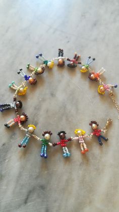 a bracelet made out of bead dolls on a marble counter top, with the beads in different colors and sizes