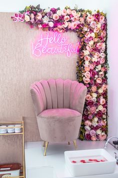 a pink chair sitting in front of a flower covered wall