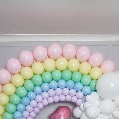 a pink flamingo balloon sitting on top of a table next to balloons in the shape of a rainbow