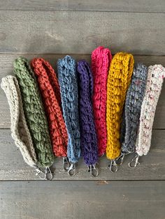 six crocheted headbands lined up on a wooden surface with metal hooks