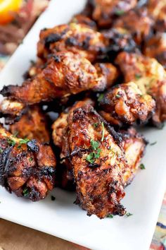 grilled chicken wings on a white plate with lemon wedges and parsley in the background