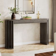 a console table with candles and flowers on it in front of a wall mounted mirror