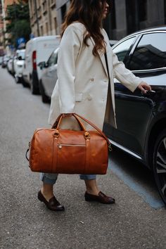 This handmade leather travel bag is made with 100% natural full grain leather which is tanned with all natural materials. There is no chemical materials in this leather.  This bag is handmade in our studio in Milan.  The lining is 100% cotton and it is easy to clean.  All the HARDWARE are made by BRASS. they are real brass and not finishing by brass color. the quality is really high and we guarantee all of the hardwares. All the bags will come with a cotton dust bag which can protect the leather and bag when it is not in use.  In options u can find Protection cream to add to your purchase. It will make the bag waterproof and will renew it after some use.  Dimensions :  Wide: 52 Cm / 21  inches Hight: 29 Cm / 11.5 inches  Deep: 26 Cm / 10.5 inches  Handle drop: 15 Cm / 6inches Long adjustab Duffle Bag Photoshoot, Brown Weekender Bag With Luggage Sleeve For Business Trips, Brown Weekender Bag For Business Trips, Brown Leather Travel Bag For Business Trips, Brown Tote Travel Bag For Business Trips, Brown Leather-lined Weekender Bag For Business Trips, Brown Satchel Duffle Bag For Business Trips, Cognac Smooth Grain Leather Duffle Bag For Travel, Cognac Smooth Grain Weekender Bag For Travel