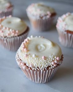 some cupcakes with white frosting and pink sprinkles on them