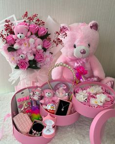 a pink teddy bear sitting on top of a table filled with flowers and other items