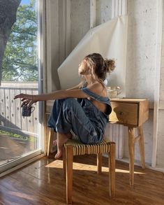 a woman sitting on top of a chair in front of a sliding glass door next to a wooden table