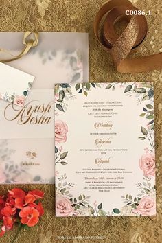 the wedding stationery is laid out next to some flowers and ribbon on top of it