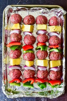 meatballs and vegetables are arranged on top of each other in an aluminum pan, ready to be cooked