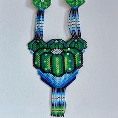 a green and blue beaded necklace hanging on a wall