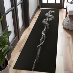 a black and white photo of a snake crawling on a door mat in a living room