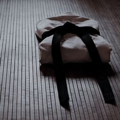 a white bag sitting on the floor with a black ribbon around it's neck