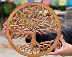 a person holding up a wooden carved tree ornament