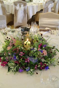 a centerpiece with flowers and candles on a table