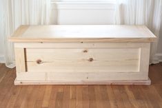 a wooden box sitting on top of a hard wood floor in front of a window