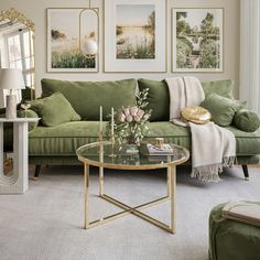 a living room with green couches and pictures on the wall above them, along with a coffee table