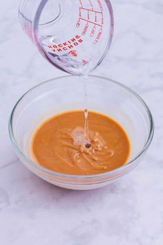 a glass bowl filled with sauce being poured into it