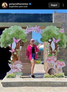 a woman standing in front of a wooden gate with trees and animals on the sides