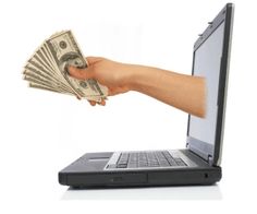 a person holding money in front of a laptop