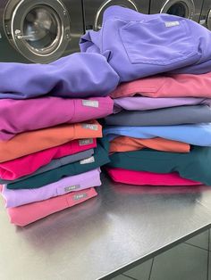 a stack of clothes sitting on top of a metal counter next to a dryer