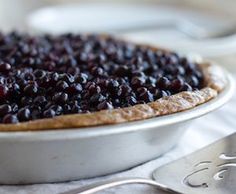 a close up of a pie on a plate with spoons and forks in the background