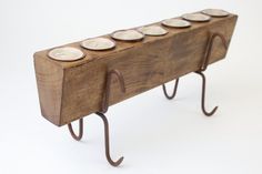 a wooden rack with five small white plates on it's sides and four metal hooks