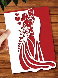 a hand holding a paper cutout of a bride and groom