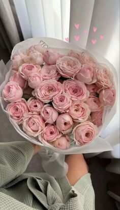 a person holding a bouquet of pink roses