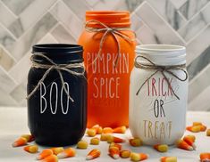 three mason jars decorated with halloween sayings and candy corn on the table next to each other