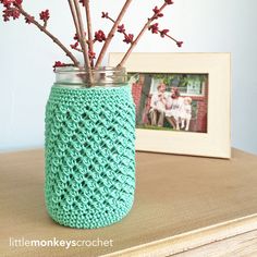 a jar with branches in it sitting on a table next to a picture frame and framed photograph