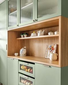 a kitchen with green cabinets and wooden shelves