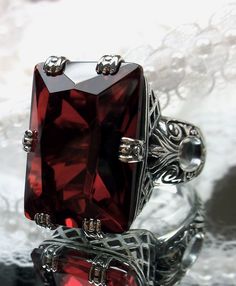 Simulated Red Ruby Ring  6 Prong Design#104 Custom Made to Order I now offer this is a brand new Art Deco reproduction ring in sterling silver. The gorgeous filigree ring is set with a flawless huge 30ct Simulated Red Ruby gemstone. The high quality rectangle cut red gemstone is 20mm in length by 15mm in width (5/8th inch by 11/16th inch). The inside of the band is marked 925 for sterling silver. Notice the beautiful swirl like craftsmanship of the silver filigree setting. Feel free to ask quest Red Garnet Ring, Antique Filigree, Fairy Pictures, Ring Heart, Heart Red, Filigree Jewelry, Gems Art, Victorian Rings, Fairytale Dress