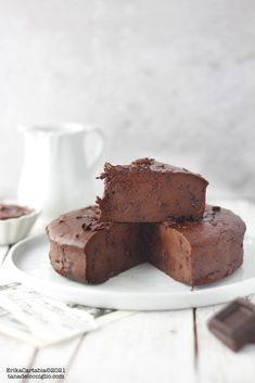 three pieces of chocolate fudge cake on a white plate next to a cup and saucer