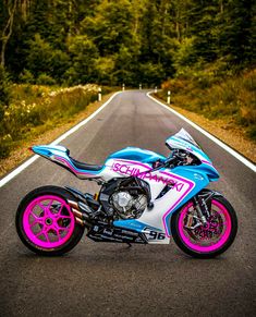 a pink and blue motorcycle parked on the side of a road