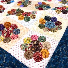 a quilted table topper with many different colored ribbons on it's edges