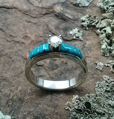 a close up of a ring on a rock with rocks in the background and blue stones around it