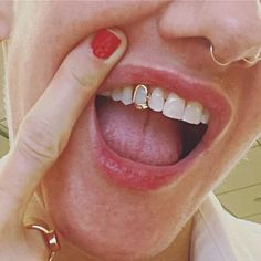 a woman holding her nose with two gold rings on it's thumb and making a silly face