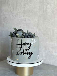 a birthday cake with blueberries and leaves on top