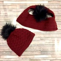 two crocheted hats with black fur pom - poms