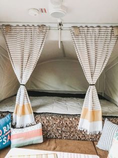 the inside of a camper with curtains and pillows