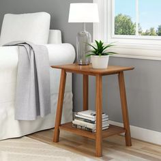 a small wooden table with a potted plant on it next to a white couch