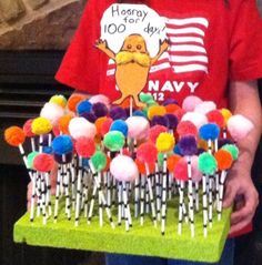 a young boy holding a tray full of lollipops and marshmallows