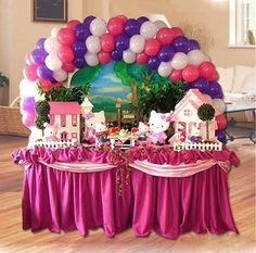 the table is set up with pink and purple decorations, including hello kitty houses, trees, and balloons