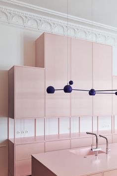 a kitchen with pink cabinets and blue balls hanging from the ceiling