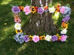 flowers arranged in the shape of a letter on grass next to a tree with leaves and branches