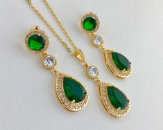 I've create this luxurious green emerald cubic zirconia bridal teardrop set in gold plated brass setting. This set includes: #Earrings feature a large teardrop with pear cut green emerald cubic zirconia center surrounded by tiny round zirconia crystals. Teardrop dangles from a earstud with brilliant cut red ruby cubic zirconia center and surrounded by tiny round zirconia crystals and a round cubic zirconia connector. Total length of the earring is 4.8 cms. #Necklace pendant features a large tear Green Wedding Jewelry, Green Gold Jewelry, Pink Pearl Earrings, Bridesmaids Jewelry, Wedding Jewelry Set, Gold Bridal Earrings, Green Bridesmaid, Cubic Zirconia Jewelry, Cubic Zirconia Earrings