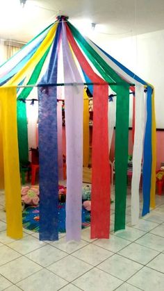 a colorful tent with ribbons hanging from it's sides in the middle of a room