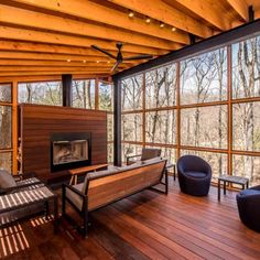 a living room with wooden floors and large windows on the side of the wall that overlooks trees