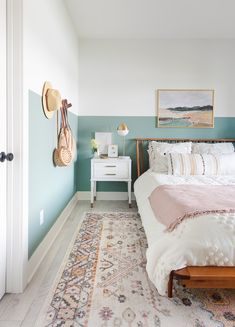 a bedroom with a bed, rug and pictures on the wall above it in shades of blue