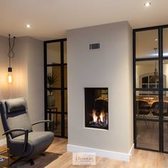 a living room with a chair, fireplace and glass doors that open to the outside