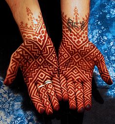 two hands with hendi designs on them, one is red and the other is white